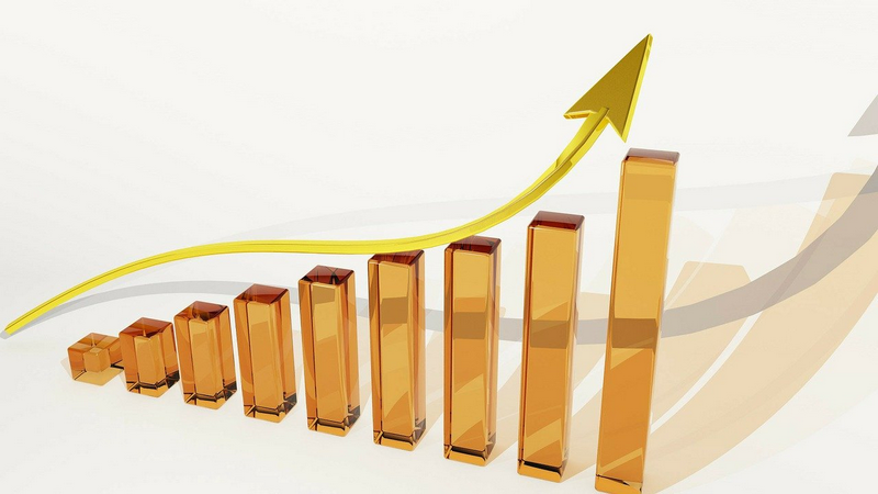 A 3D illustration of a rising gold bar chart with a yellow arrow soaring upwards, symbolizing growth or progress.